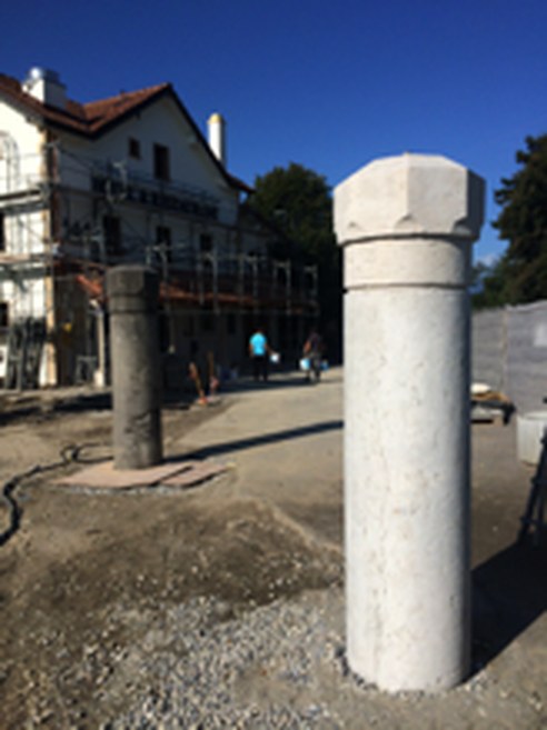 Deux bornes en pierre sur un chantier : au fond celle qui n'a pas encore été traitée, grise, au premier plan la même après sablage, revenue à la pierre claire