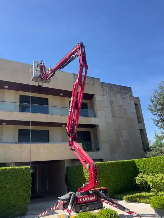Nacelle élévatrice déployée le long de la façade en pierre d'un immeuble de bureaux pour un nettoyage haute pression